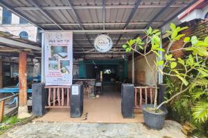a restaurant entrance with a sign and a plant at RedDoorz at Marina City Waterfront in Pembunuh