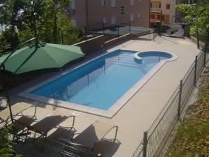 a large swimming pool with chairs and an umbrella at Apartmani Adriatica 2 in Dramalj