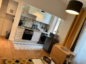 a kitchen with white cabinets and a table in a room at Appartement de 27 m2 agréable et lumineux idéalement situé au coeur de la ville de Pierrefitte-sur-Seine in Pierrefitte-sur-Seine