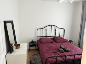a bedroom with a bed with red sheets and pillows at Appartement de 27 m2 agréable et lumineux idéalement situé au coeur de la ville de Pierrefitte-sur-Seine in Pierrefitte-sur-Seine