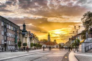 eine Stadtstraße bei Sonnenuntergang mit Leuten, die auf der Straße spazieren in der Unterkunft Avanti Apartments in Białystok