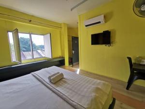 a yellow bedroom with a bed with a towel on it at Abby by the river in Ipoh