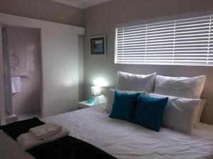 Un dormitorio con una cama blanca con almohadas y una ventana en 93 On Main Self Catering, en Gonubie
