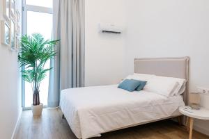 a bedroom with a white bed and a potted plant at Main Lofts Valencia in Valencia