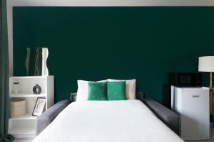 ein Schlafzimmer mit einer grünen Wand und einem weißen Bett in der Unterkunft A Deux Pas de la Magie - Idéal DisneyLand & Paris in Bussy-Saint-Georges