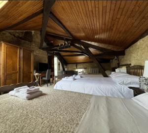 a bedroom with two beds with white sheets and a wooden ceiling at Hôtel de France et de Russie in Thiviers