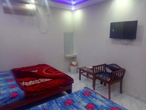 Zimmer mit 2 Betten, einem TV und 2 Stühlen in der Unterkunft Four Season Guest House in Islamabad