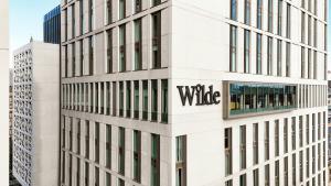 曼彻斯特Wilde Aparthotels Manchester City Centre的上面有柳条标志的高大的白色建筑