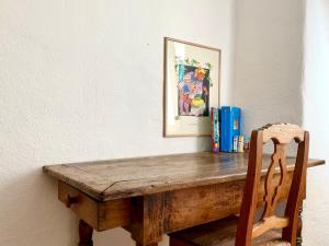 een houten tafel met een stoel en een foto aan de muur bij La corte del meleto - appartamento in stile Valdostano in Saint-Pierre