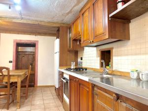 een keuken met houten kasten, een tafel en een wastafel bij La corte del meleto - appartamento in stile Valdostano in Saint-Pierre +29 foto's