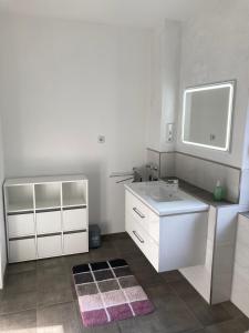 a white bathroom with a sink and a mirror at 2-Zimmer-Ferienwohnung 55 qm, bei Berlin in Velten