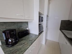 a kitchen with white cabinets and a coffee maker on the counter at Très bel appartement accès direct sur plage, vue sur mer - 2 pièces - 4 pers in Saint-Jean-de-Monts +19 photos