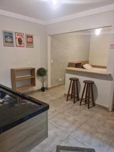 a kitchen with a counter and stools in a room at Marmeu Tombo com Hidro Aquecida Privativa in Guarujá