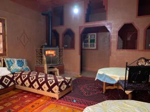 a living room with two beds and a fireplace at Auberge Des Jardins du Dades in Boumalne