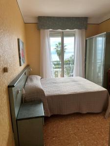 a bedroom with a bed and a large window at Hotel Svizzera in Arma di Taggia