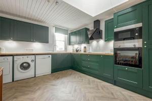 a kitchen with green cabinets and a washer and dryer at The Cross Keys Apartment - 85D Market Street in St. Andrews