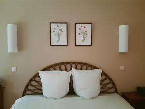 two pillows on a bed with two pictures on the wall at Hostellerie Du Lys in Lamorlaye