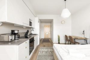 トゥルクにあるKotimaailma - Valoisa yksiö Turun Pukkilassaの白いキッチン(白いキャビネット、テーブル付)