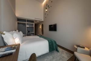a bedroom with a white bed and a tv at Dolinas Climbing Hotel in Porto de Mós