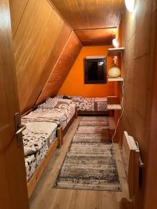 two beds in a room with a tv and a rug at Vikendica Šipovac in Jahorina