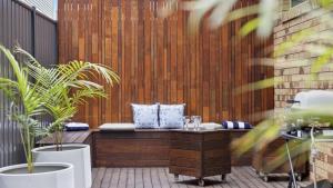 a patio with two potted plants and a bench at Boronia Oasis - Tranquil Oasis By The Creek, Sleeps 4 in Sawtell