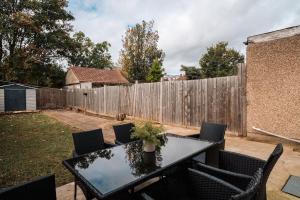a table and chairs in a backyard with a fence at Contractor-Friendly 3-Bed, Games Room, Pool Table! in Enfield Lock