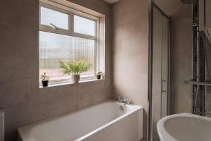 a bathroom with a tub and a sink and a window at Contractor-Friendly 3-Bed, Games Room, Pool Table! in Enfield Lock +38 photos