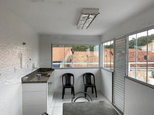 a kitchen with two chairs and a dog looking out the window at Aconchego do peró in Cabo Frio