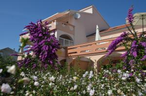 a building with purple flowers in front of it at Apartments Jadranka in Novalja