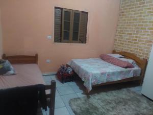 a small bedroom with two beds and a window at Casa da rafaa in Itanhaém