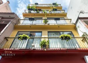 a yellow building with potted plants on a balcony at Mersey Ben Thanh Saigon Apart'Hotel in Ho Chi Minh City