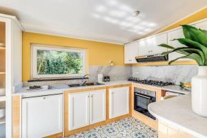 a kitchen with white cabinets and a window at Villa Chez Piè Panoramic Views Pool and Guest Services in SantʼAgata sui Due Golfi
