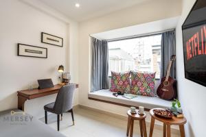 a room with a desk and a window with a guitar at Mersey Ben Thanh Saigon Apart'Hotel in Ho Chi Minh City