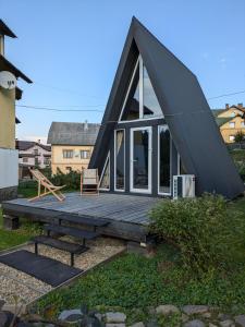 a house with a black roof and a wooden deck at Солодка Мить in Slavske