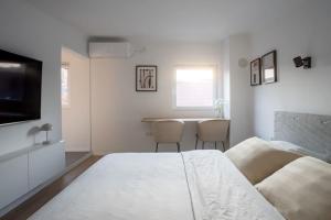 a white bedroom with a bed and a table at Apartment Kaptol in Zagreb
