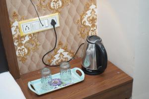 a tea kettle and glasses on a wooden table at Hotel Shubhshree in Indore