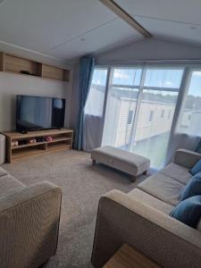 a living room with a couch and a tv andwindows at Cresswell Towers in Morpeth