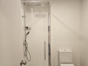 Una ducha con puerta de cristal al lado de un inodoro. en Urban Oasis - Spa, Pool and Kitchen, en Auckland 17 fotos más