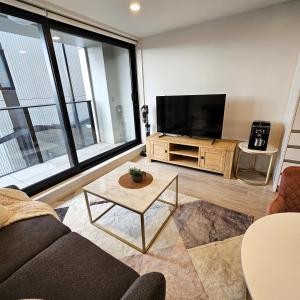 Una sala de estar con un sofá y un televisor de pantalla plana. en Urban Oasis - Spa, Pool and Kitchen, en Auckland