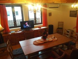 a dining room with a wooden table and a television at Cottage House in Stožec