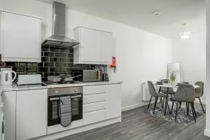 ロンドンにある3 bed home by Canning Town stationの白いキャビネットとテーブルと椅子のあるキッチン