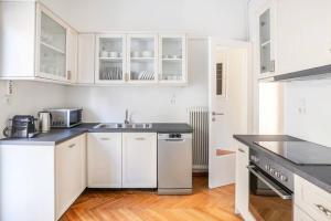 a white kitchen with white cabinets and a sink at Modern Apt opposite the Acropolis Museum in Athens