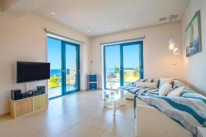 a living room with a couch and a television at Villa Dejavu Thalassa by Villa Plus in Agios Nikolaos