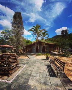 a building with a palm tree and a bench at Chalé e Cachoeira Sítio Igrejinha Serra da Bocaina in Bananal