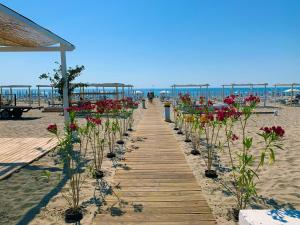 a wooden pathway with flowers on the beach at La finestra sulla piazza in Pisticci