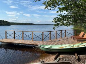 un molo con una barca e una sedia sull'acqua di Holiday Home Haapala by Interhome a Karjalaisenniemi