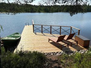 un molo con due sedie e una barca su un lago di Holiday Home Haapala by Interhome a Karjalaisenniemi