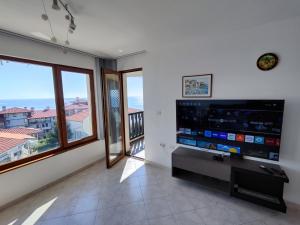 a living room with a flat screen tv and a balcony at Sun Coast Apartment in Sveti Vlas