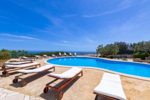 a swimming pool with lounge chairs and the ocean at Villa Tenuta Ai Fichi con piscina esclusiva in Leuca