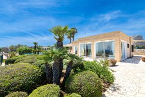a house with palm trees in front of it at Villa Tenuta Ai Fichi con piscina esclusiva in Leuca